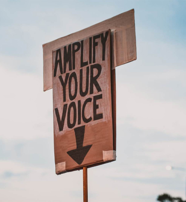 a wood sign stating about amplify your voice
